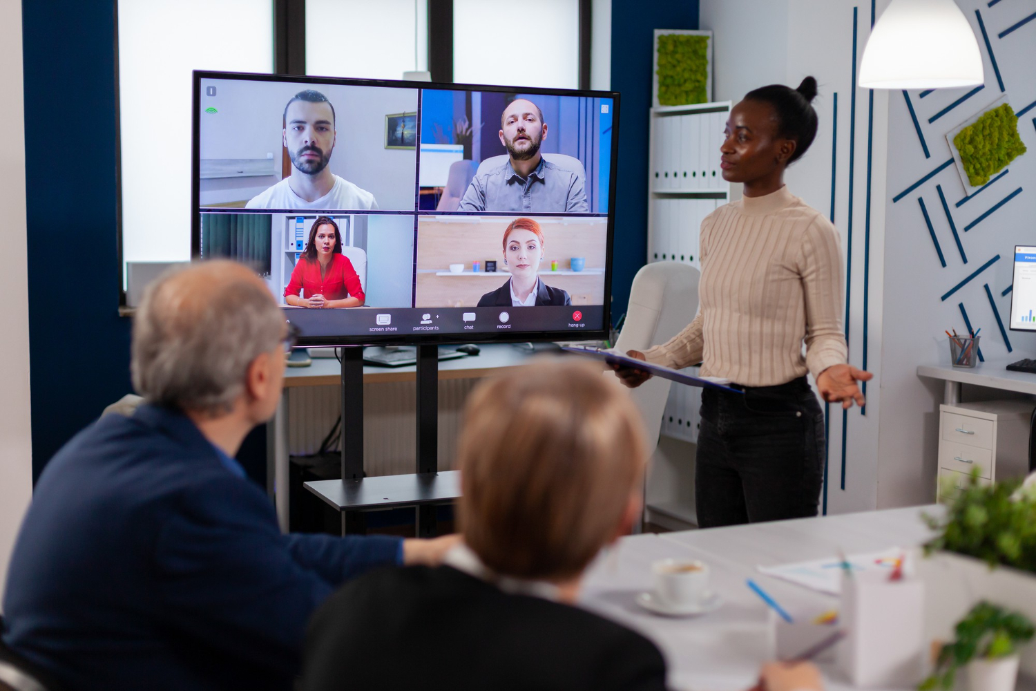 04-black-manager-woman-talking-with-remotely-colleagues-video-call-tv-screen-presenting-new-business-partners